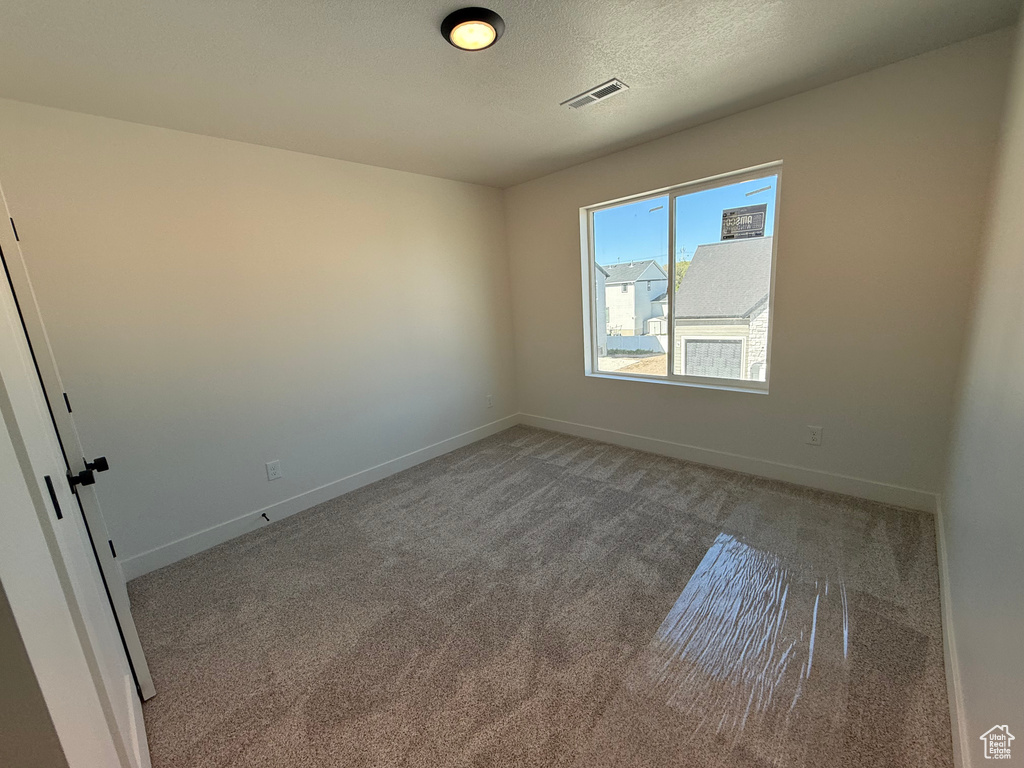 Unfurnished room with carpet floors, baseboards, and a textured ceiling