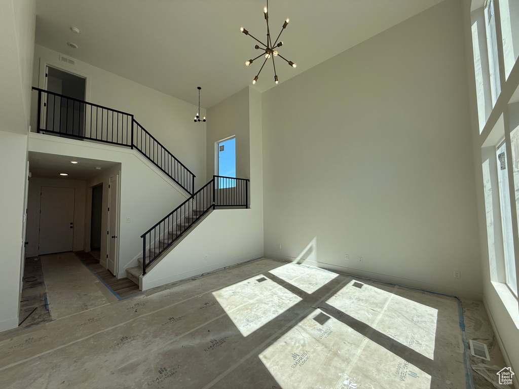 Stairs featuring a chandelier, a high ceiling, and healthy amount of natural light