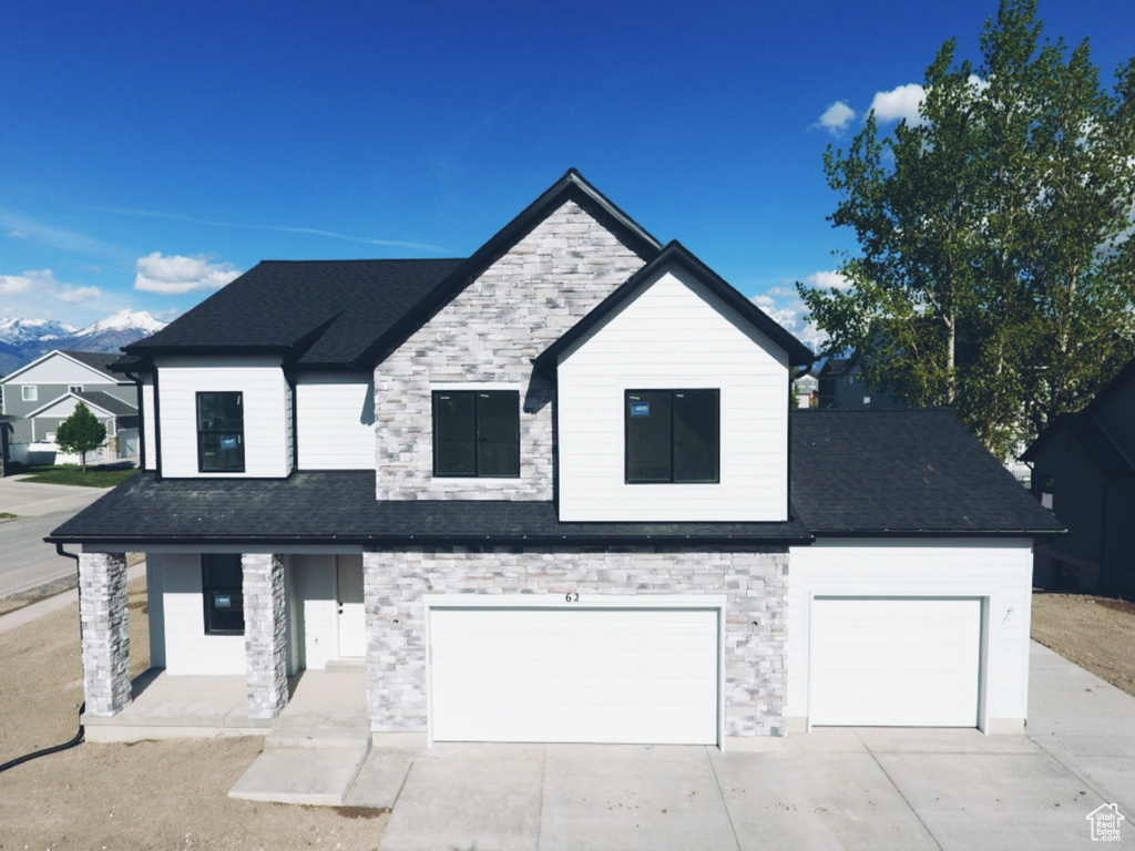 Modern farmhouse style home featuring a garage, concrete driveway, roof with shingles, and stone siding
