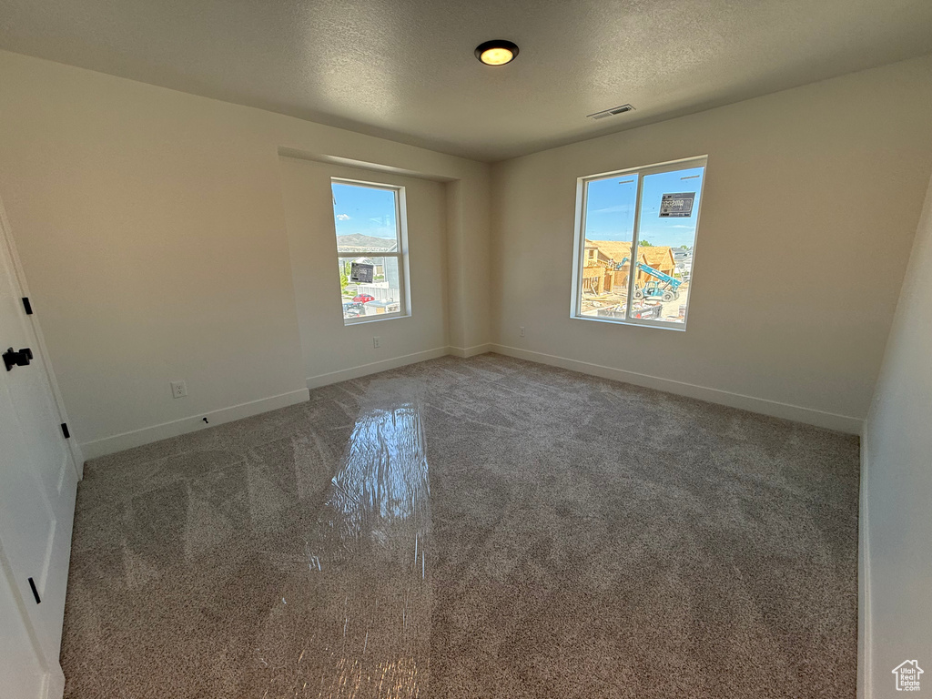 Carpeted spare room featuring baseboards and a textured ceiling