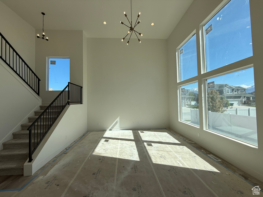 Unfurnished dining area with a chandelier, stairway, a towering ceiling, and recessed lighting