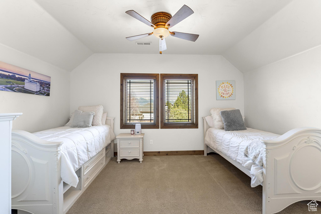 Bedroom featuring light carpet, visible vents, vaulted ceiling, and a ceiling fan