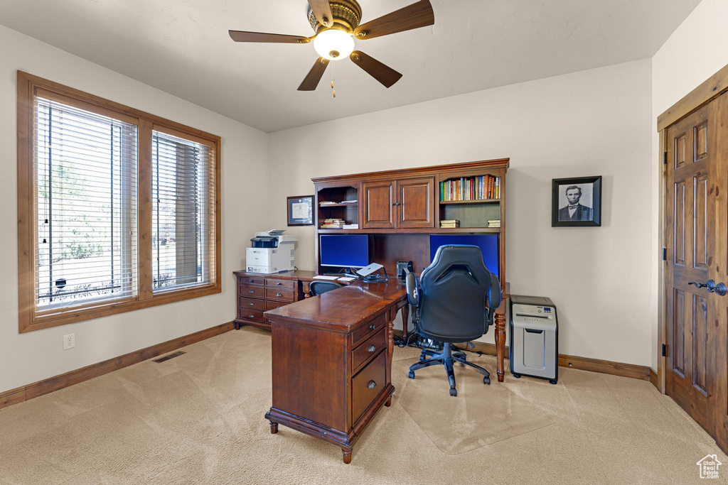 Office area featuring light carpet, baseboards, a ceiling fan, and visible vents