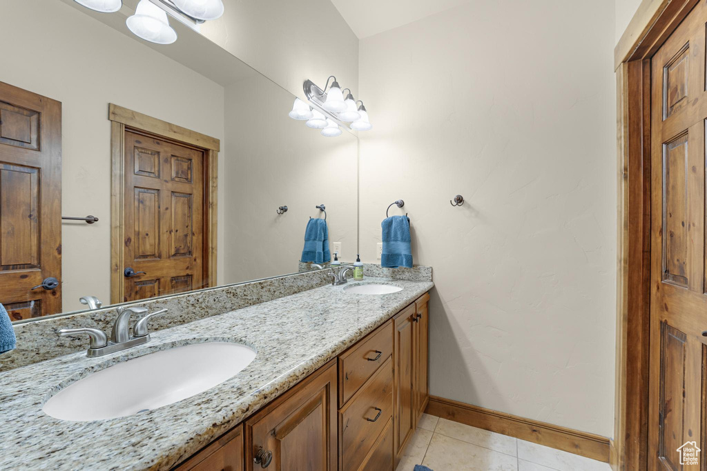 Full bathroom with double vanity, a sink, tile patterned flooring, and baseboards