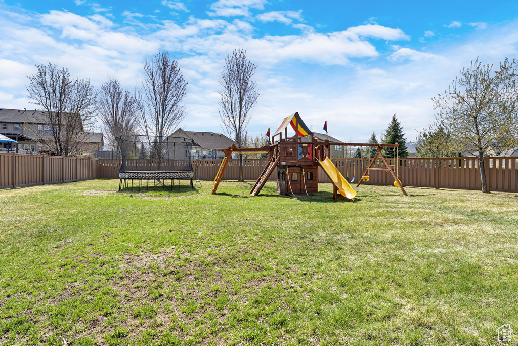 View of yard featuring a trampoline, a fenced backyard, and a playground