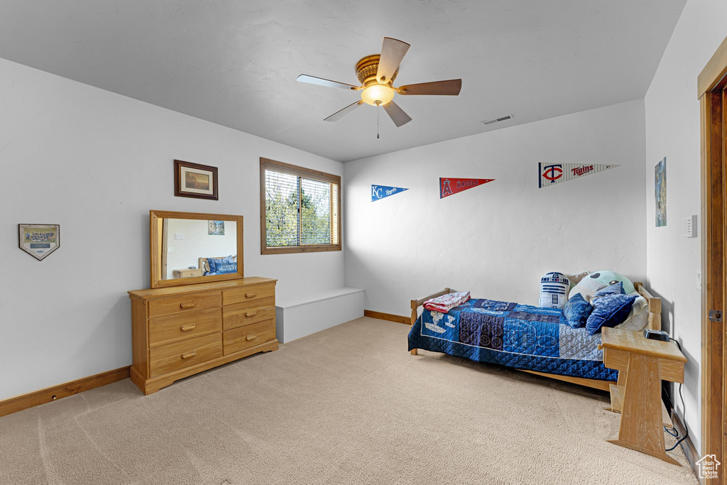 Bedroom with light colored carpet, baseboards, and ceiling fan