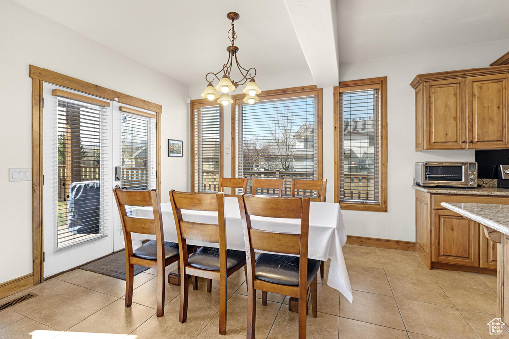 Dining area featuring visible vents, a chandelier, light tile patterned flooring, baseboards, and a toaster