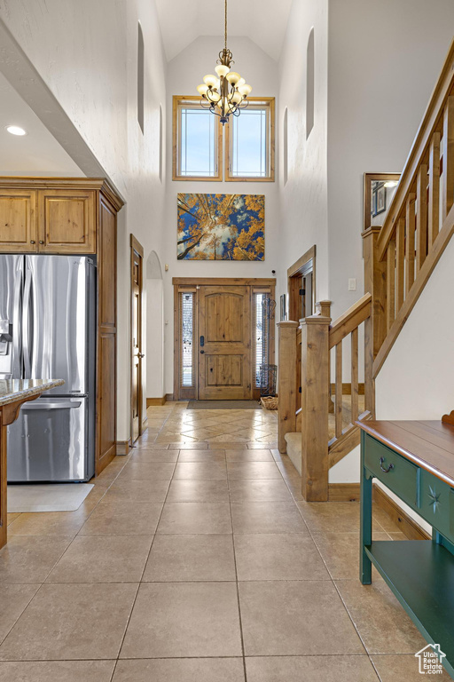 Foyer featuring a chandelier, plenty of natural light, stairway, and high vaulted ceiling