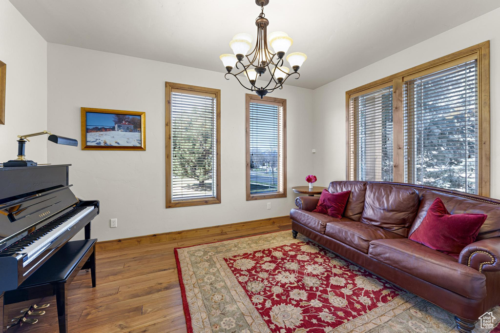 Living area with baseboards, a notable chandelier, and hardwood / wood-style flooring