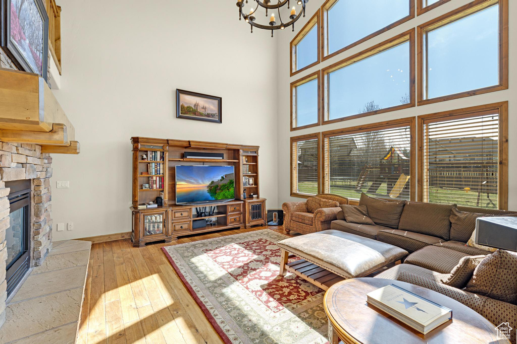 Living room featuring a notable chandelier, hardwood / wood-style floors, a high ceiling, and baseboards