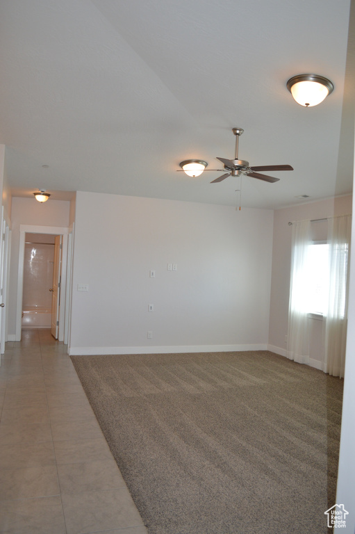 Spare room with light tile patterned floors, ceiling fan, light colored carpet, and baseboards