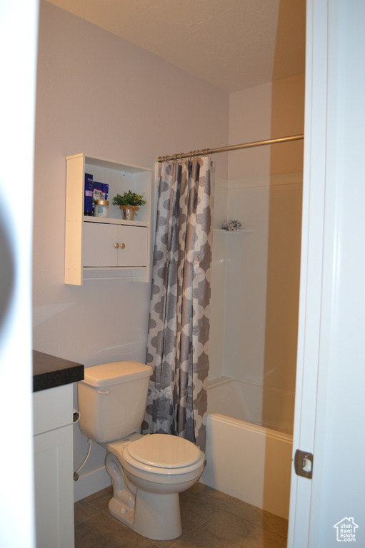 Bathroom featuring toilet, baseboards, tile patterned flooring, and shower / tub combo with curtain
