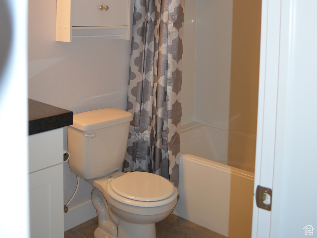 Bathroom featuring toilet, baseboards, tile patterned flooring, and shower / tub combo with curtain