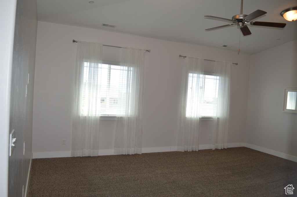 Spare room featuring carpet floors, baseboards, a ceiling fan, and visible vents