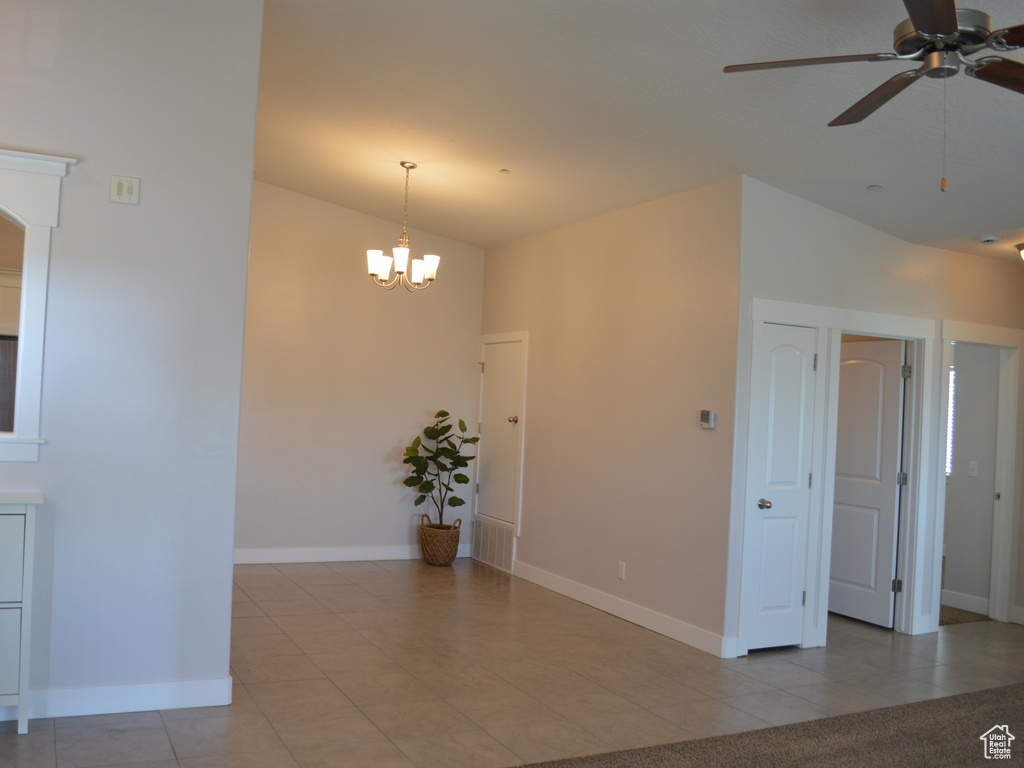 Unfurnished room with arched walkways, light tile patterned floors, ceiling fan with notable chandelier, and baseboards