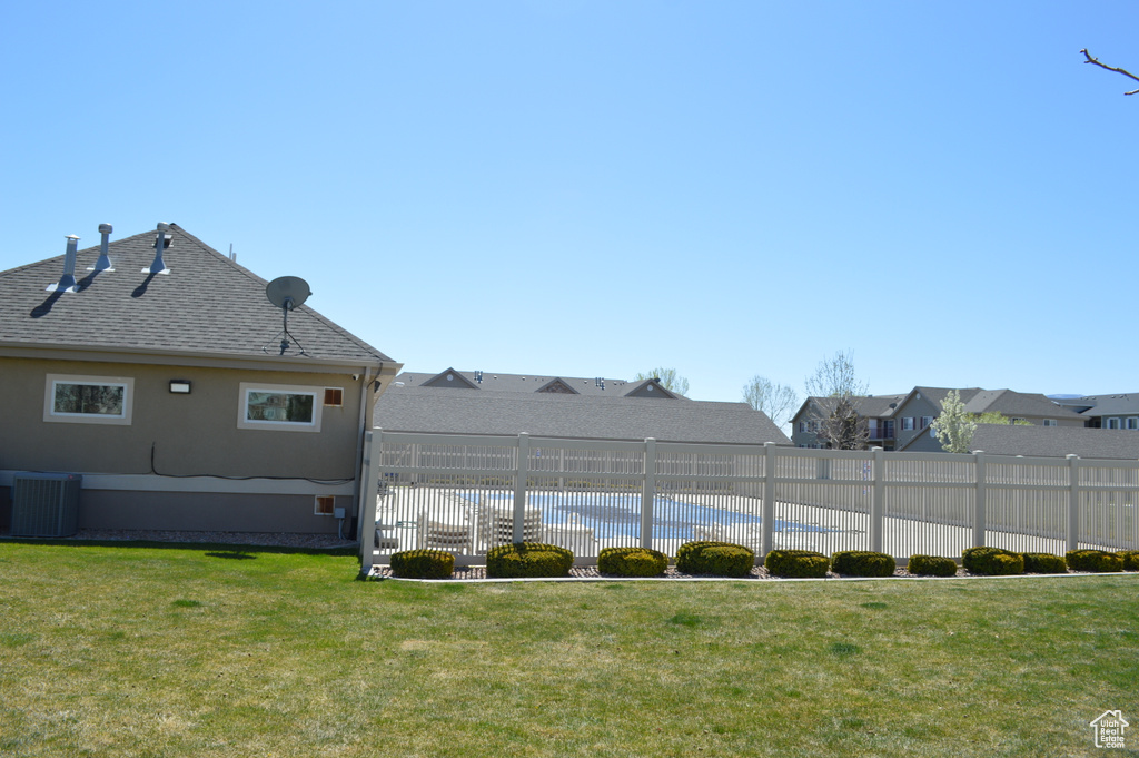 View of yard with fence, a fenced in pool, and central air condition unit