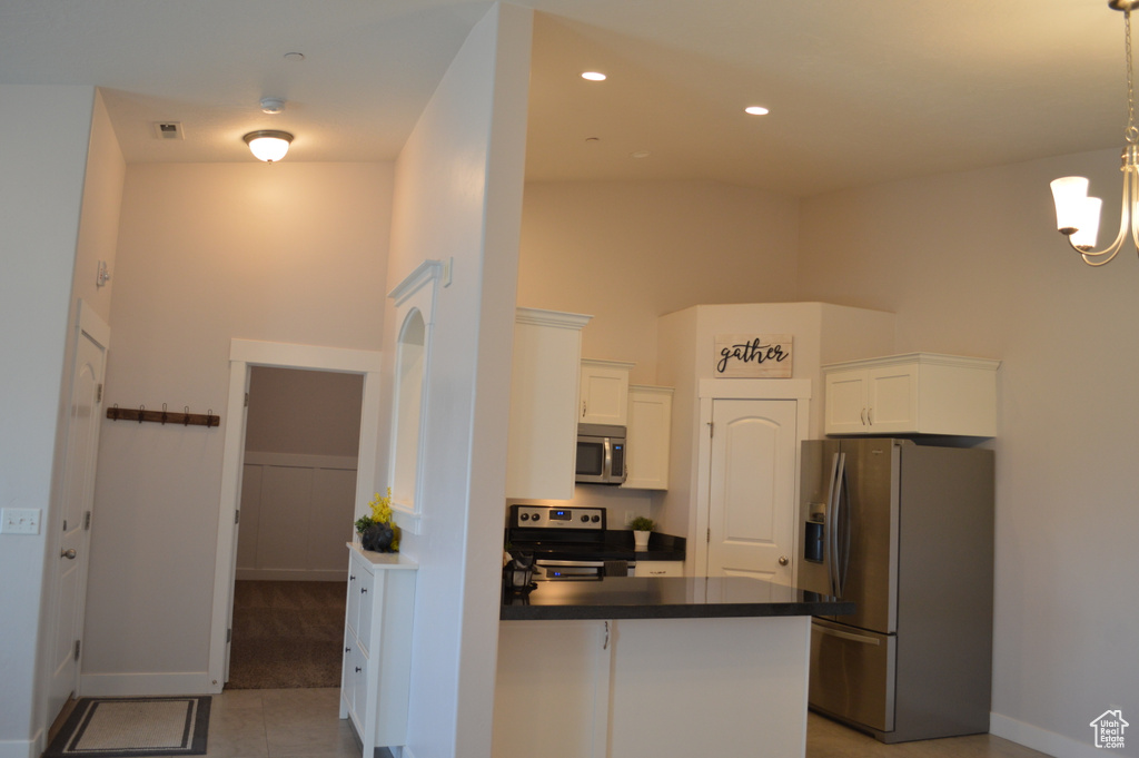 Kitchen with visible vents, white cabinets, dark countertops, a peninsula, and stainless steel appliances
