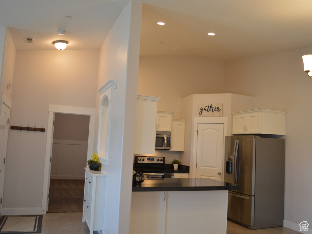 Kitchen with visible vents, white cabinets, dark countertops, a peninsula, and stainless steel appliances