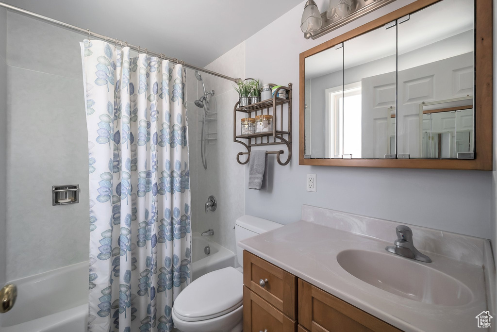Bathroom featuring shower / bath combination with curtain, toilet, and vanity