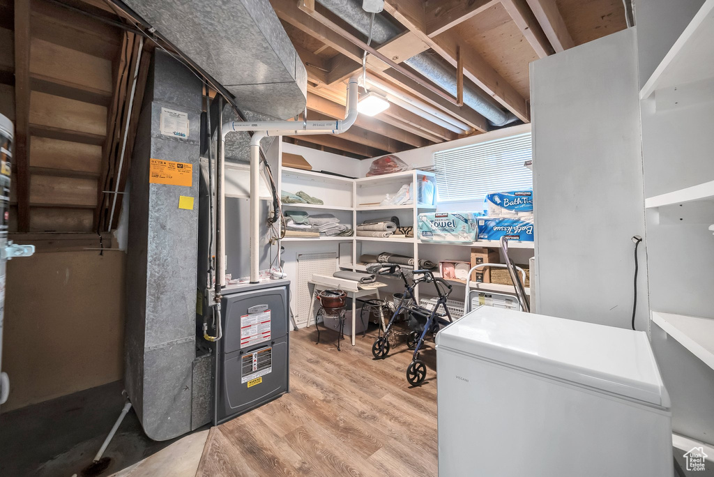 Interior space featuring heating unit, light wood-style flooring, and white refrigerator