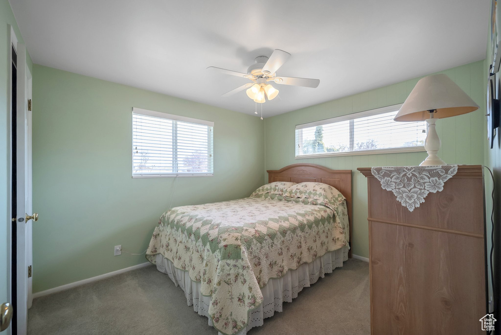 Bedroom featuring light colored carpet, baseboards, and a ceiling fan