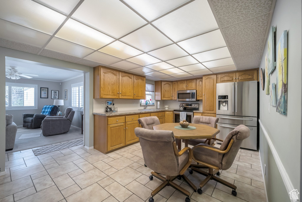 Kitchen with a sink, baseboards, brown cabinetry, light countertops, and appliances with stainless steel finishes