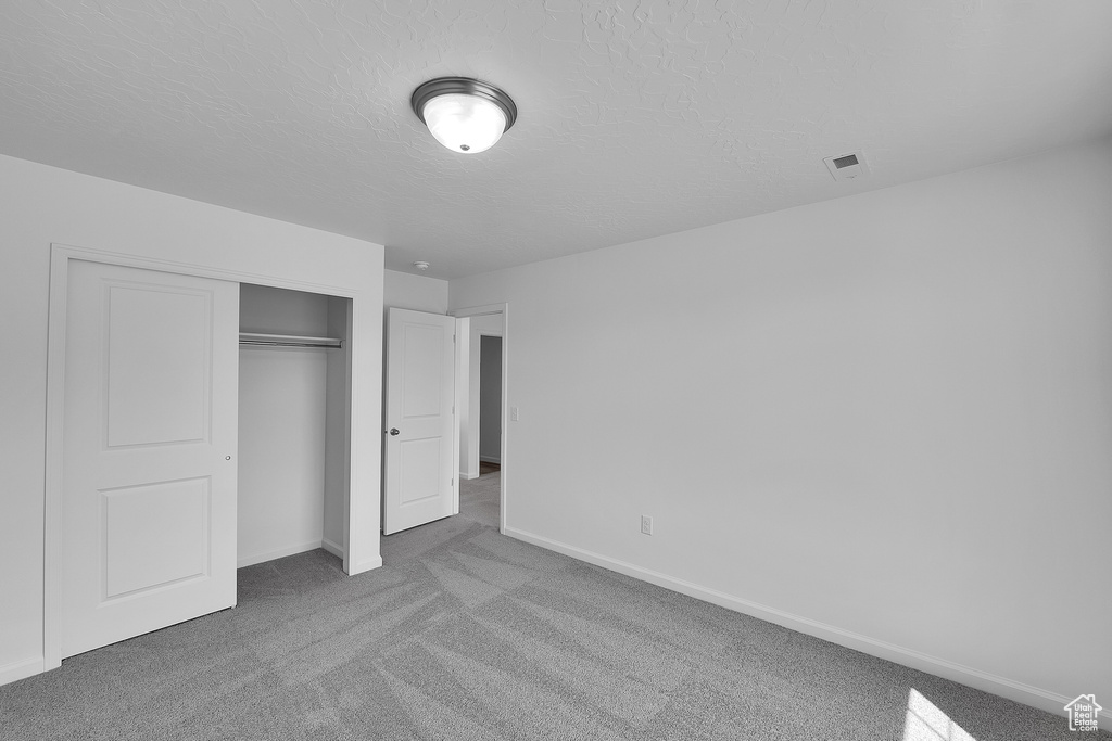 Unfurnished bedroom with carpet floors, a closet, baseboards, and a textured ceiling