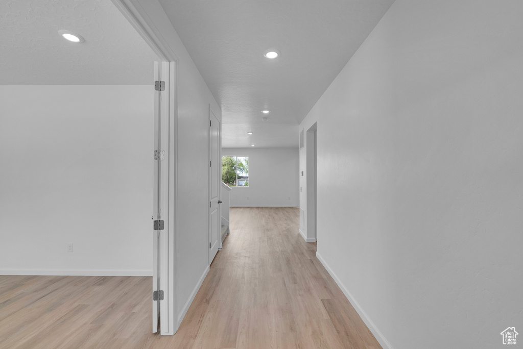 Hall with recessed lighting, light wood-style flooring, and baseboards