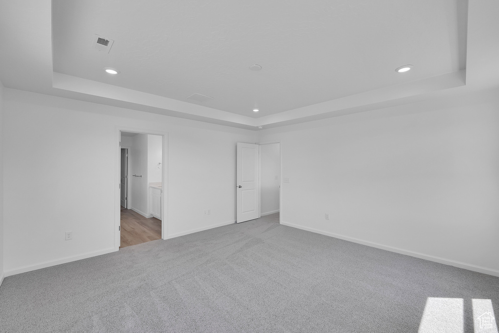 Unfurnished room with a raised ceiling, carpet, recessed lighting, and baseboards