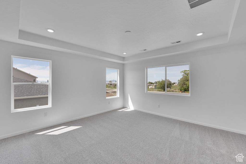 Carpeted spare room featuring a tray ceiling, baseboards, and recessed lighting