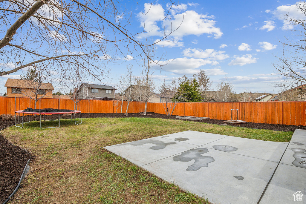 View of yard featuring a patio, a fenced backyard, and a trampoline