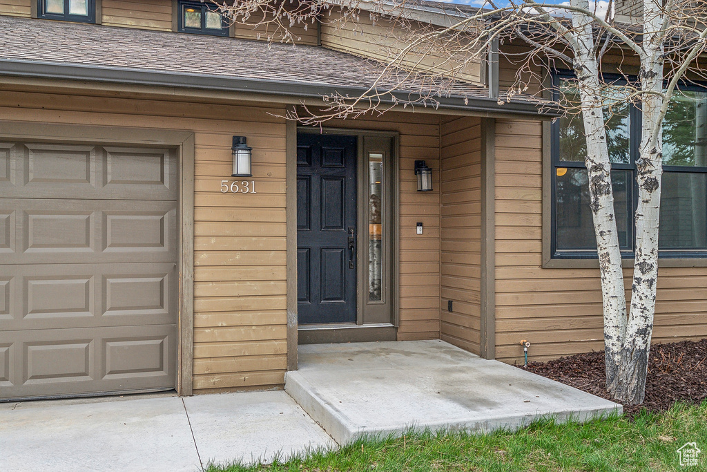 Property entrance featuring roof with shingles and a garage