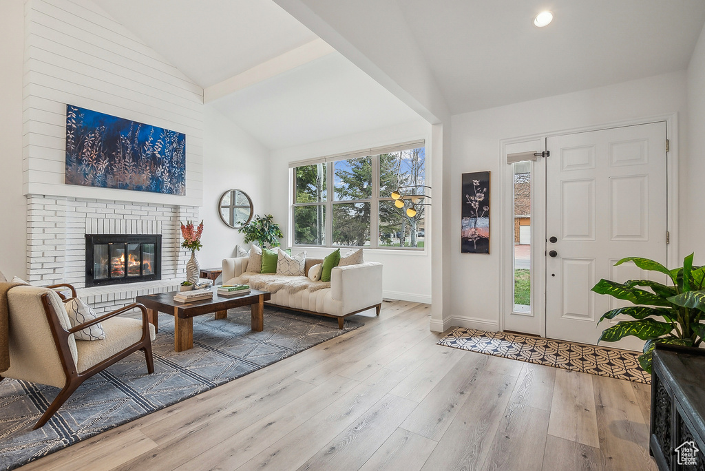 Living room featuring high vaulted ceiling, hardwood / wood-style flooring, baseboards, a brick fireplace, and recessed lighting