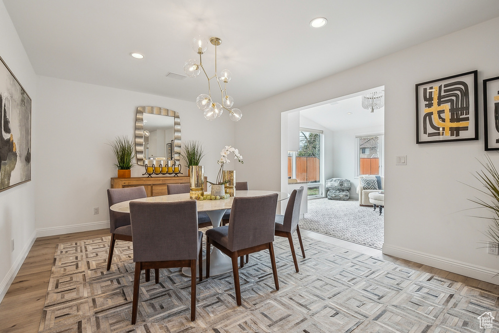 Dining room featuring recessed lighting, light wood-style flooring, baseboards, and a notable chandelier