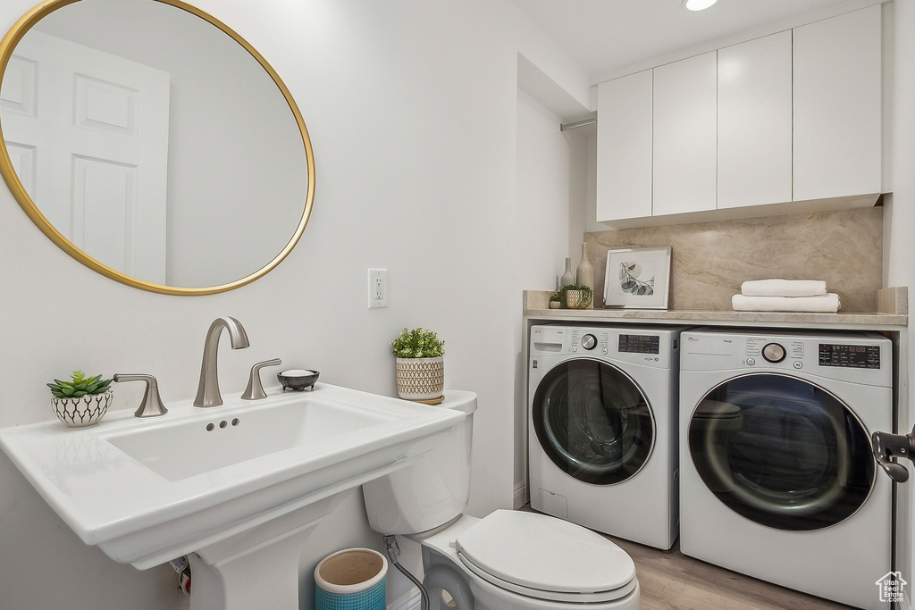 Clothes washing area featuring light wood-style flooring, laundry area, and washer and clothes dryer