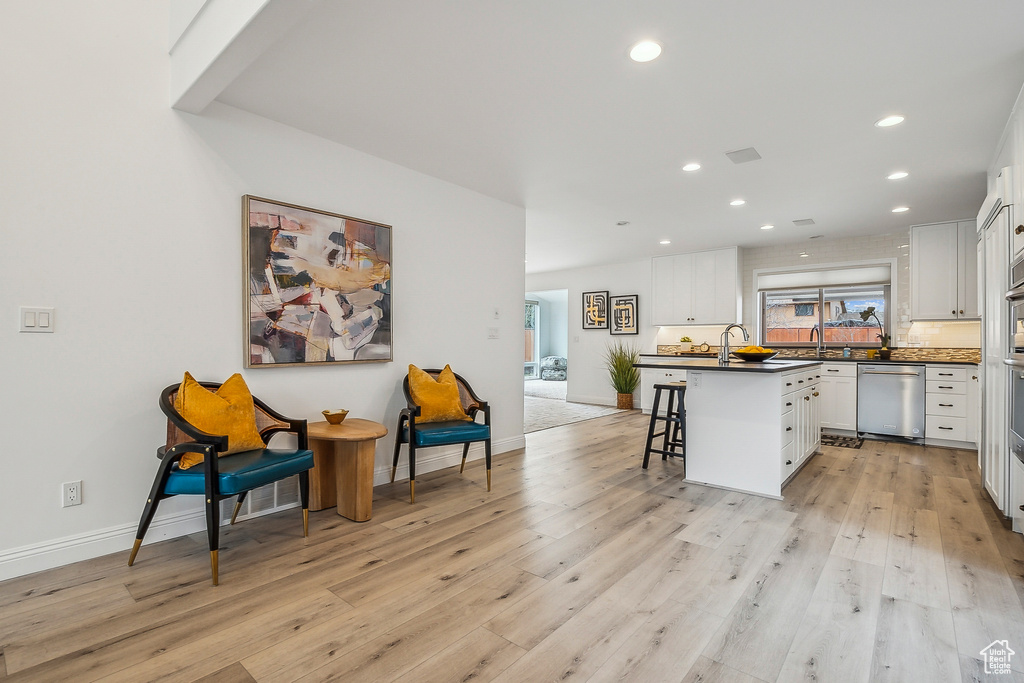 Kitchen featuring dark countertops, light wood-style flooring, white cabinetry, and a breakfast bar area