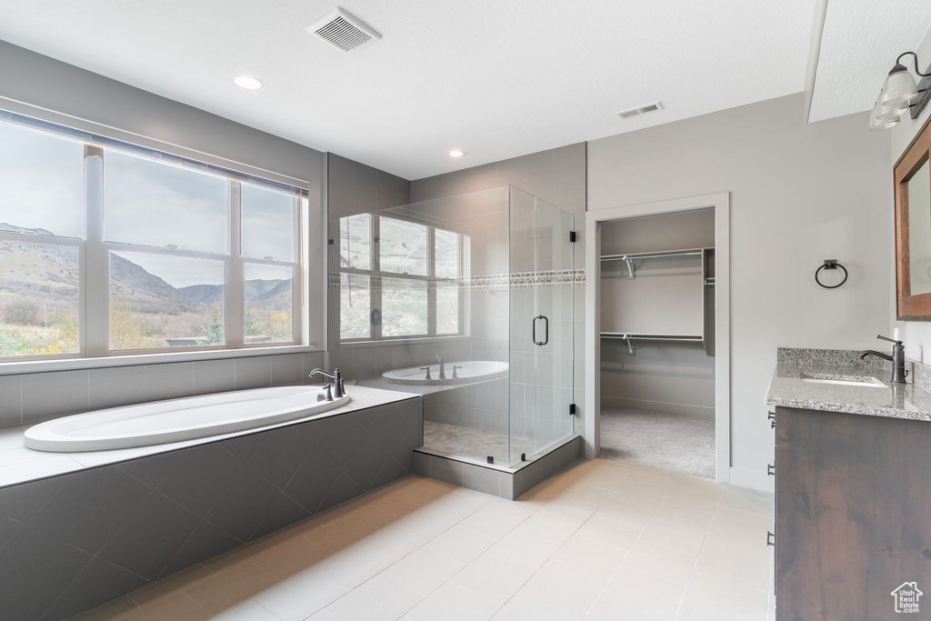 Bathroom featuring a bath, visible vents, a spacious closet, a shower stall, and vanity