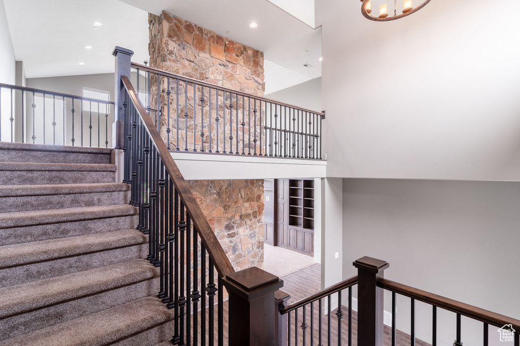 Staircase with a high ceiling, an inviting chandelier, and recessed lighting