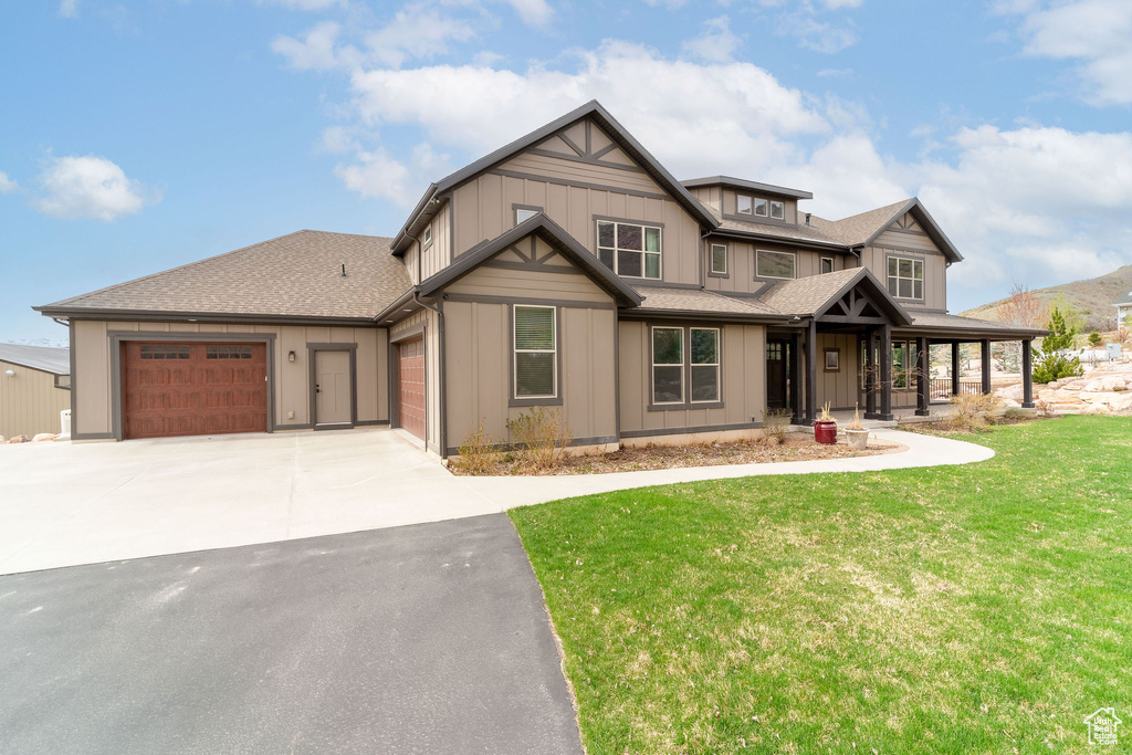Craftsman-style house with a porch, concrete driveway, a garage, board and batten siding, and a front yard
