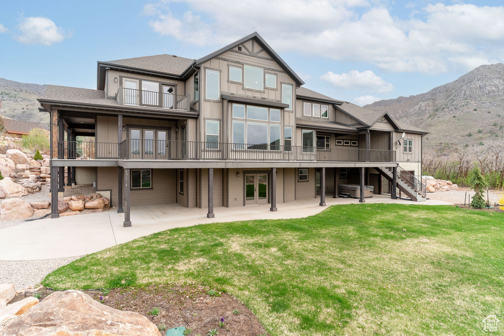 Back of house with a patio area, a balcony, a lawn, french doors, and a mountain view