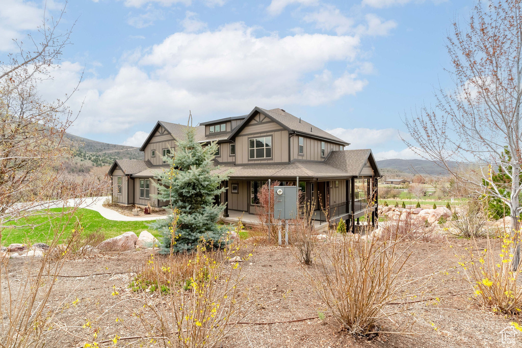 View of front facade featuring board and batten siding, a shingled roof, covered porch, and a mountain view