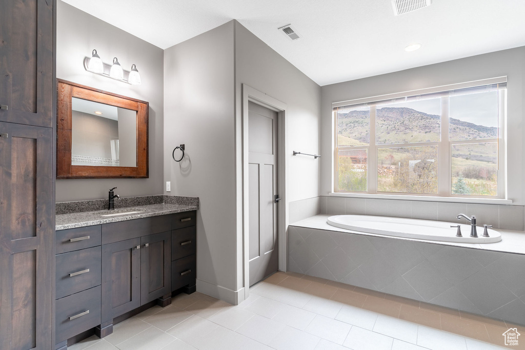 Bathroom with a garden tub, vanity, tile patterned floors, and visible vents