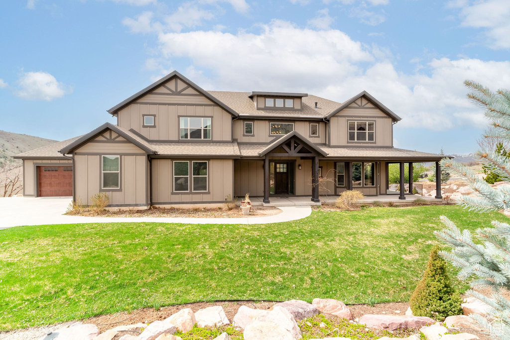 Craftsman-style home featuring driveway, a porch, a garage, a shingled roof, and a front yard