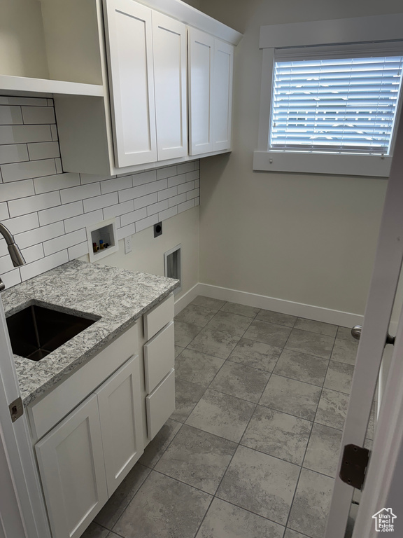 Clothes washing area with a sink, hookup for an electric dryer, cabinet space, baseboards, and washer hookup
