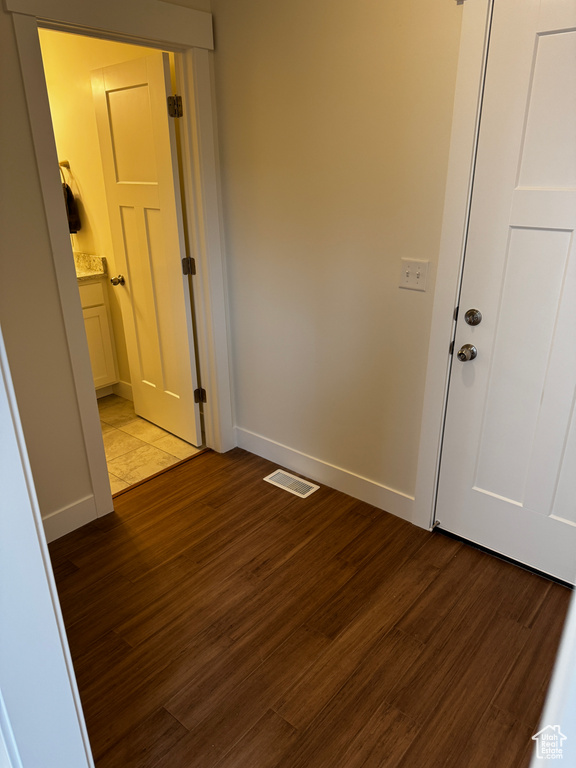 Hall featuring baseboards, wood finished floors, and visible vents