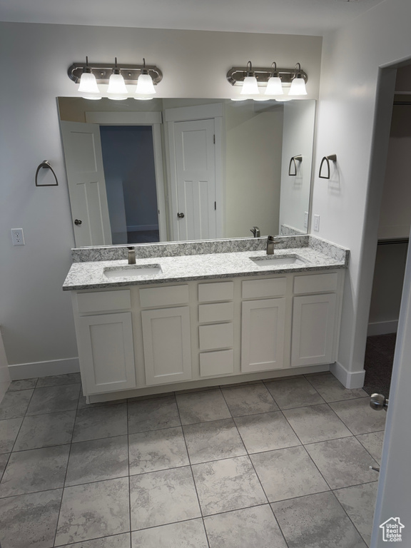 Bathroom featuring baseboards, a sink, and double vanity