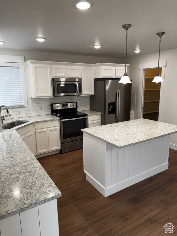 Kitchen with a center island, a sink, white cabinets, appliances with stainless steel finishes, and dark wood-type flooring