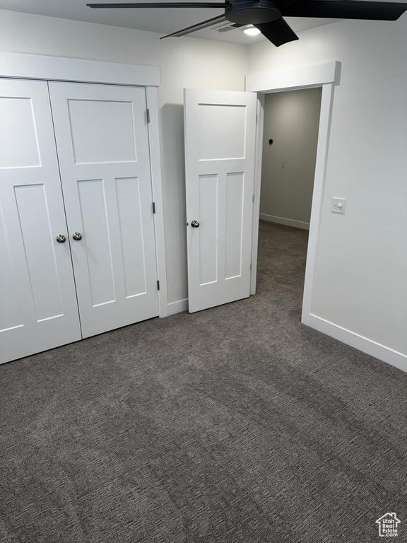 Unfurnished bedroom featuring dark carpet, a closet, baseboards, and ceiling fan