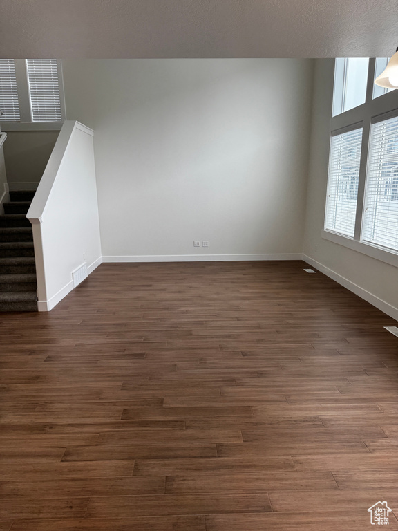 Unfurnished living room with visible vents, baseboards, and dark wood-type flooring