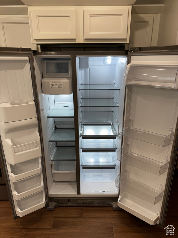Interior details with refrigerator with glass door, white cabinetry, and dark wood-style flooring